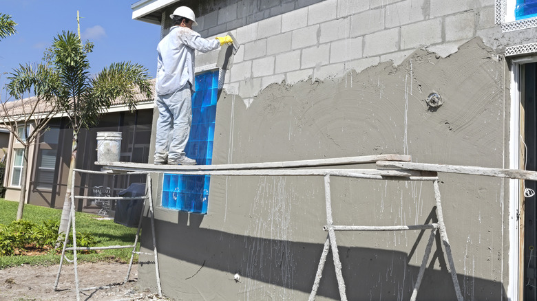 Real contractor Putting a base coat of stucco on a house